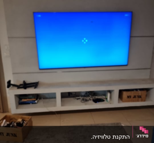 טלוויזיה מותקנת על קיר עם מדף תחתון
